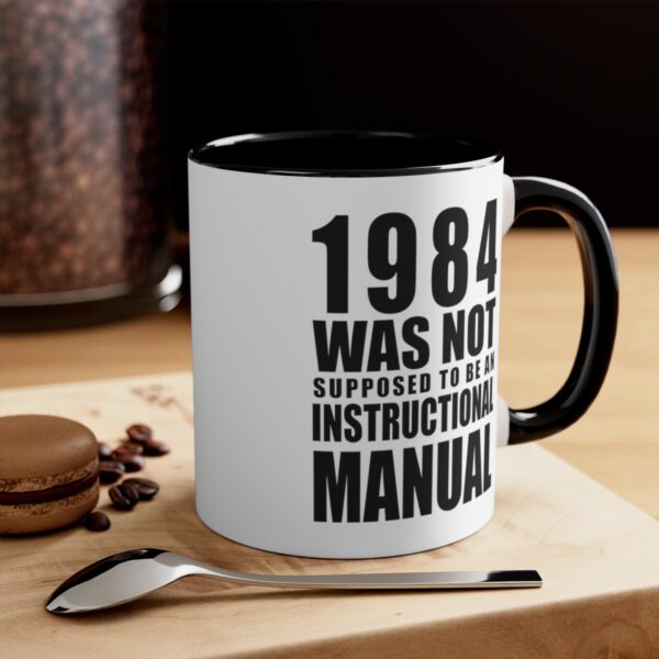 1984 Was Not Supposed To Be An Instructional Manual White Coffee Mug With Black Handle And Interior – On A Table With A Spoon .