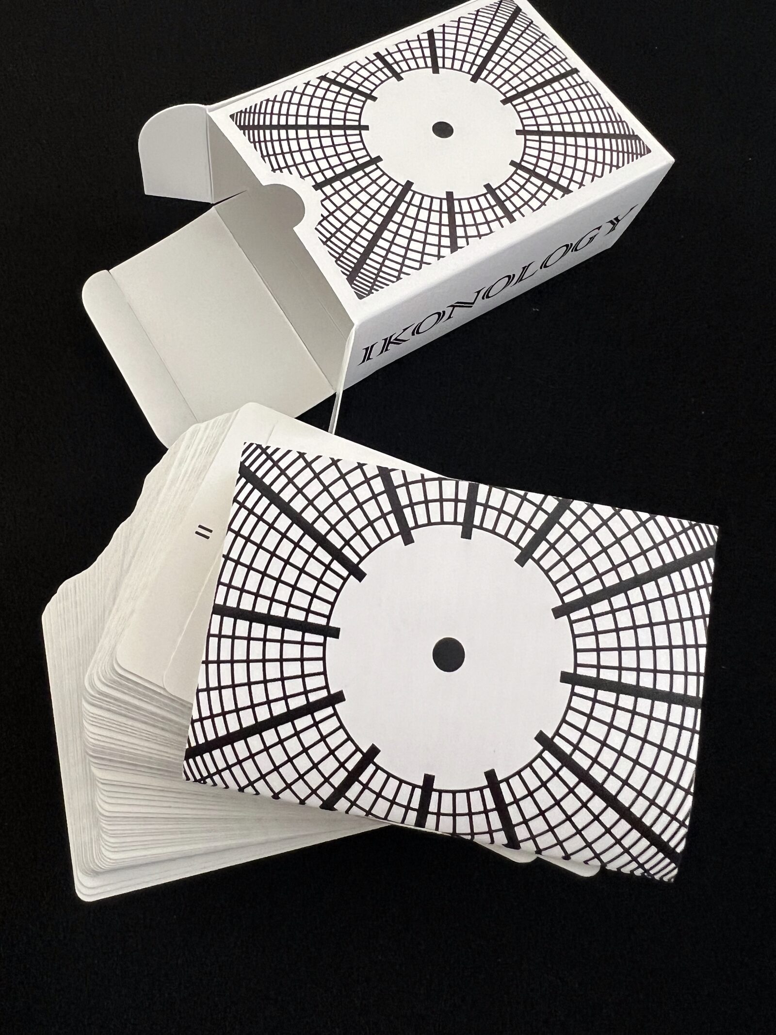 Ikonology tarot deck in its white tuck box beside a stack of cards with the clock-face card back